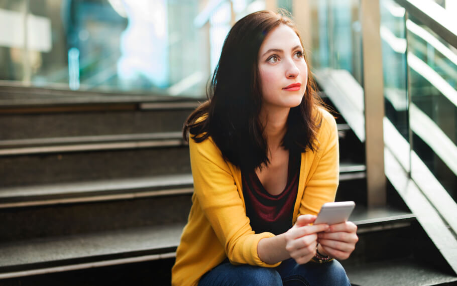 A woman is outside on her phone, waiting for an appointment.